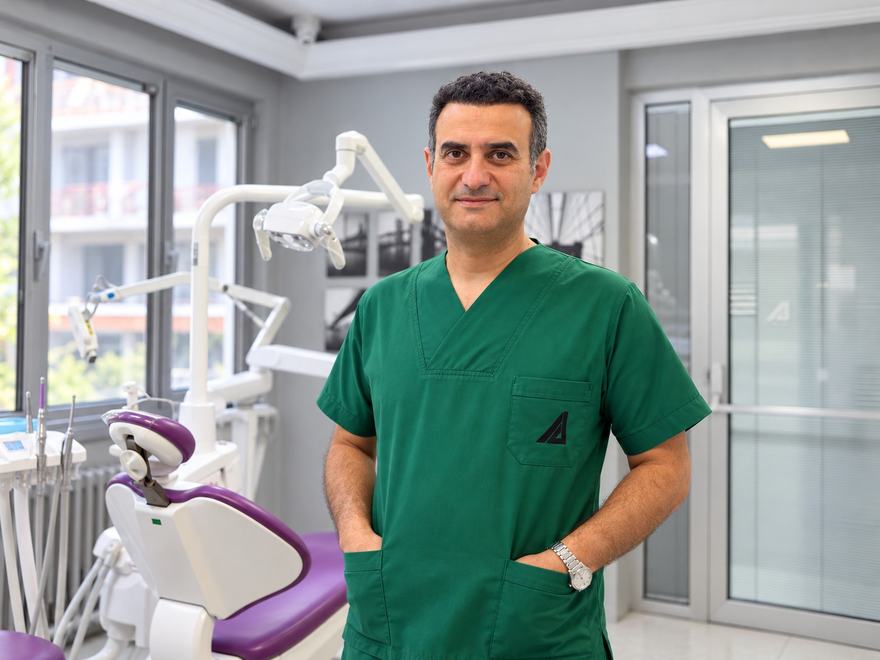 Dr. Taylan Akça, Akça Diş kliniğinde yeşil önlüğüyle diş ünitinin yanında